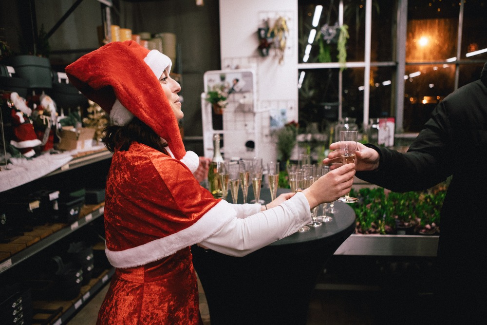 Een kerstvrouw die een glaasje bubbels geeft op een kerstmarkt